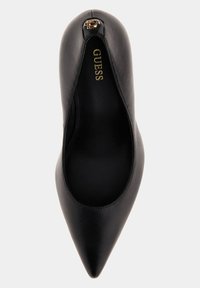Scarpa nera in pelle con tacco alto e punta affilata, caratterizzata da un accento dorato con logo sul tacco. Texture liscia, design elegante e aperture sui lati.
