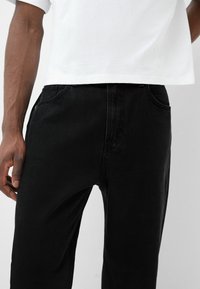 Černé džíny z denimu s rovnými nohavicemi a pěti kapsami. Látka má hladkou strukturu a minimální blednutí.