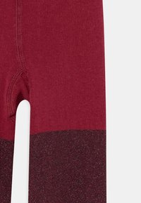 Collants de malha bordeaux com uma faixa metálica texturizada na parte inferior, com uma seção superior lisa e costura reforçada.
