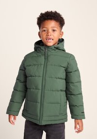 Green puffer jacket with horizontal panels, detachable hood, front zipper closure, and side pockets. Worn over a black shirt and jeans.
