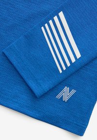 Blauwe textiel met een gladde, gestructureerde stof. Bevat witte verticale strepen en een logo in de hoek, met nette stiksels langs de randen.