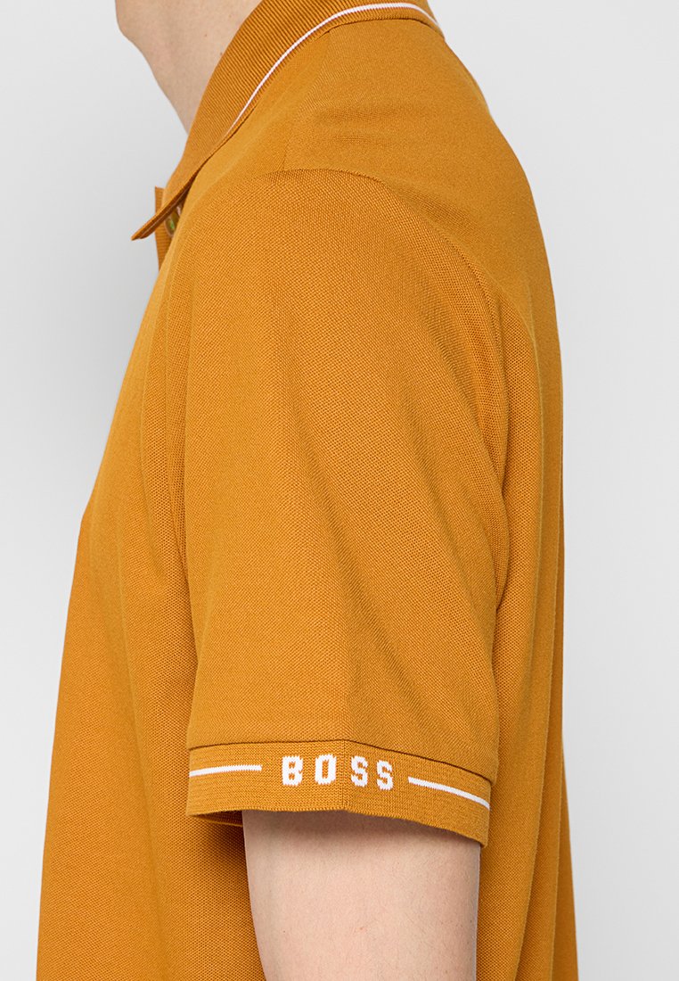 Polo arancione con tessuto testurizzato, caratterizzato da un colletto bianco con strisce a contrasto e il logo "BOSS" ricamato sulla manica.