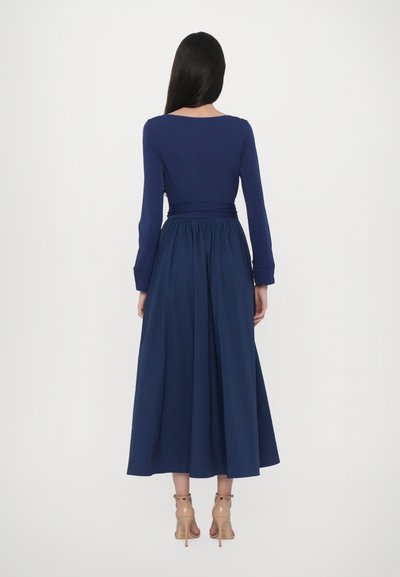 Langsleeve marineblauw jurk met een getailleerde bodice en een uitlopende rok. Bevat een verzameld middel en een gladde stoftextuur.