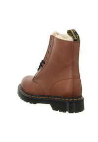 Bota de cuero marrón con un interior acolchado, cordones negros, ojales de metal y costuras amarillas. La suela es texturizada con un dibujo en relieve.