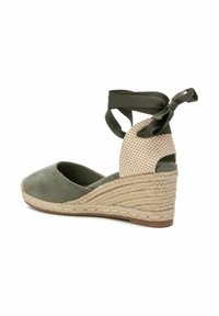 Espadrilles de cuña de ante verde con un tacón de yute trenzado. Presentan una correa de tela a cuadros en el tobillo atada en la parte posterior. Diseño de punta redondeada.