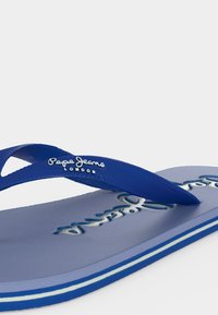 Μπλε σαγιονάρα με υφή στο λουράκι και στη σόλα, με το λογότυπο "Pepe Jeans London" στο λουράκι και ανάγλυφο branding στην πάτο.