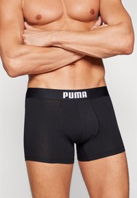 Black men’s boxer briefs made of smooth fabric with a PUMA logo on the waistband. Features a fitted design and short leg length.