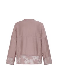 Haut à manches longues rose poudré avec une coupe ample, présentant une bordure en dentelle florale le long de l'ourlet et des poignets, vu de dos.