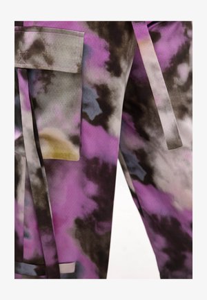 Nahaufnahme eines lila-schwarzen Batikstoffs mit einer Tasche und langen Stoffriemen, die lose hängen.