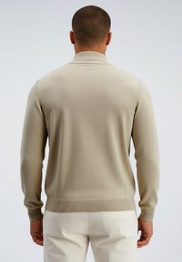 Suéter beige de punto con cuello alto, puños y dobladillo acanalados. Mostrado desde atrás, con un patrón texturizado en la tela.