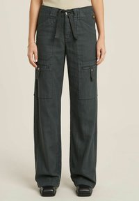 Pantaloni cargo verde scuro con vestibilità rilassata, dotati di passanti per cintura, tasche laterali e vita con cordoncino. Realizzati in tessuto leggero.