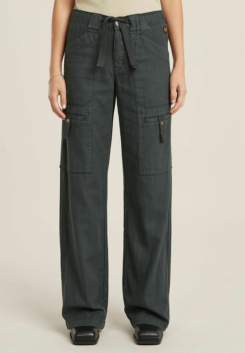 Pantaloni cargo verde scuro con vestibilità rilassata, dotati di passanti per cintura, tasche laterali e vita con cordoncino. Realizzati in tessuto leggero.