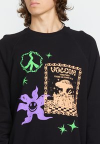Zwarte sweatshirt met levendige grafische prints in oranje, paars en groen. Ontwerpen omvatten een paddenstoel, een lachende bloem en een vredessymbool.
