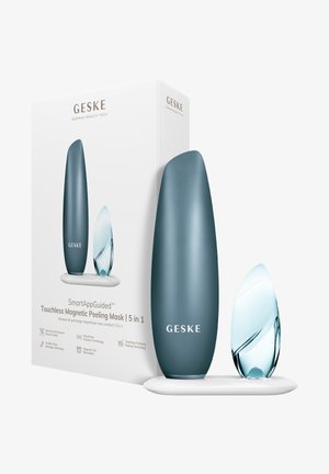 GESKE SmartAppGuidet berøringsfri magnetisk peelingmaske med to slanke enheder på en hvid opladningsstand og produktemballage.