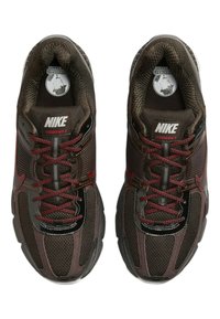 Bruna Nike Vomero 5-sneakers har meshpaneler, kontrasterande röda snören och en slank design. Noterbar logotyp på tungan och sidorna.