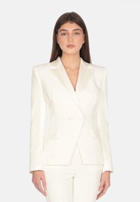 Blazer bianco doppiopetto con rever in raso e due tasche frontali, realizzato in tessuto morbido, con una vestibilità su misura.