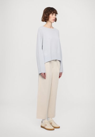 Hele sinine lühikese lõikega sviiter ribatud äärega, kombineeritud beežide laia jala pükstega ja beežide tennistega, millel on värviline triibu detail.