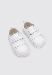 Chaussures en cuir blanc avec deux bandes Velcro ajustables, bout arrondi, semelle en caoutchouc et doublure en tissu doux. Présente un logo sur la sangle.