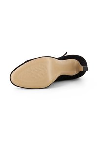 Chaussure à talon haut en daim noir avec une semelle en caoutchouc beige lisse. Présente un bout arrondi et un design minimaliste, avec un petit talon pour un soutien supplémentaire.
