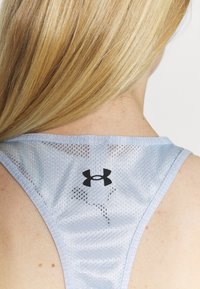 Top sin mangas de malla azul claro con diseño de espalda nadadora. Presenta el logo negro de Under Armour y una tela transpirable con pequeñas perforaciones.