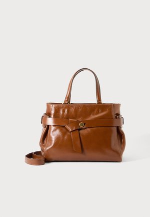Braune Lederhandtasche mit zwei Griffen, einem umlaufenden Riemen, der durch einen goldenen Knopf gesichert ist, und einem abnehmbaren Schulterriemen vor weißem Hintergrund.