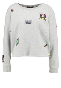 Sweat-shirt gris raccourci en coton, orné de diverses patchs brodés, dont une cassette audio et des motifs floraux, avec des poignets côtelés.