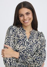 Langärmlige dunkelblaue Bluse mit cremefarbener abstrakter Musterung, geknöpftem Halsausschnitt und gerafften Manschetten, aus leichtem, strukturiertem Stoff gefertigt.