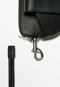 Clutch in pelle nera con finitura texturizzata, dotata di cerniera e accessori in argento, e di una tracolla attaccata con clip.
