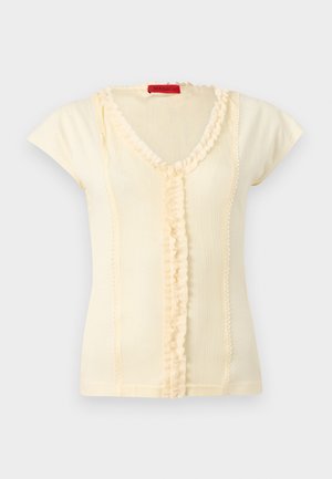 Krém színű, rövid ujjú bordás felső V-nyakkal, középen és a nyakkivágásnál fodros szegéllyel, piros MAX&Co. címkével.