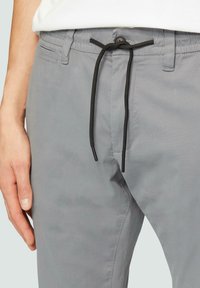 Grijze katoenen broek van een katoenmix met een tailleband met trekkoord en zwarte accenten. Voorzien van zijzakken en een gladde, matte textuur.