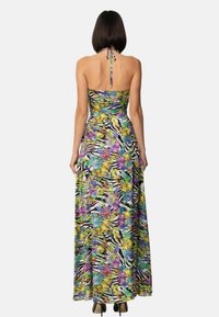 Abito maxi caratterizzato da una vivace stampa floreale e animale in viola, giallo e verde, con un corpetto aderente e design a collo a halter.