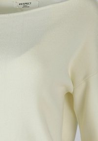 Oficialiai baltas audinys megztinis su plačiu iškirpimu ir nusileidusių pečių siūlėmis. Etiketės „GERBIMAS“ ir „MAŽAS“. Minkšta tekstūra.