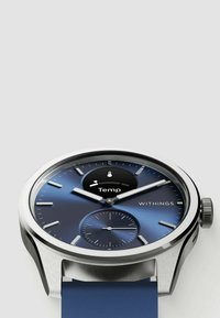 Silberne Metall-Uhr mit blauem Farbverlauf-Zifferblatt, ausgestattet mit einer Temperaturanzeige, einem Subzifferblatt und einem blauen Armband. Auffällig durch ihr elegantes Design und die klaren Markierungen.