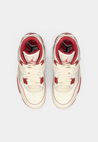 Λευκά και κόκκινα αθλητικά παπούτσια με λεπτομέρειες από δίχτυ, στρογγυλή μύτη, επίπεδη δέσιμο με κορδόνια και λαστιχένιες σόλες. Διαθέτουν λογότυπο στη γλώσσα.