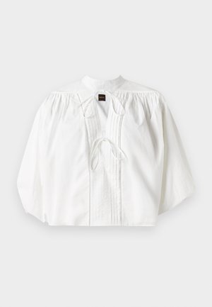 White blouse with gathered puff sleeves, a high collar, front tie closure, and vertical pleats, made from a lightweight, textured fabric.