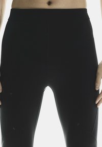 Leggings noirs en matériau extensible, avec une taille haute, un design sans couture et des détails de couture subtils.