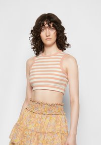 Top cropped às riscas em tons de pêssego claro e creme, com textura canelada; possui cavas largas e um decote redondo.