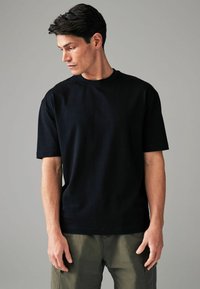 Zwart t-shirt met korte mouwen van katoen, met een ronde hals en een relaxte pasvorm. De stof lijkt glad met minimale zichtbare stiksels.
