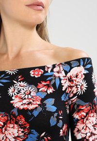 Schwarzes Off-Shoulder-Oberteil mit floralem Muster in Rot, Pink und Blau. Hergestellt aus einem glatten Stoff, hat es eng anliegende Ärmel und ein florales Design.