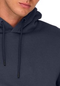 Felpa con cappuccio grigio scuro, dotata di tasca frontale, stringhe e una superficie morbida e testurizzata. Caratterizzata da una vestibilità ampia e materiale in misto cotone.