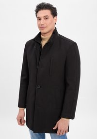 Schwarzer Mantel mit hohem Kragen, vorderer Knopfverschluss und seitlichen Taschen. Hergestellt aus strukturiertem Stoff mit dezenten Musterakzenten.