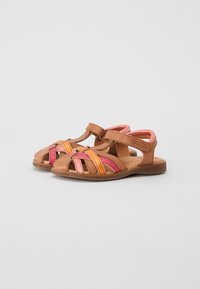 Bruine leren sandalen met kruisbanden in roze, oranje en fuchsia. Klittenbandsluiting, open neusontwerp, vlakke zool en gevoerde inlegzool.