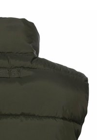 Olivgrüne Pufferweste mit hohem Kragen, gestepptem Muster, genähten Linien und einem kleinen Etikett auf der Rückseite.