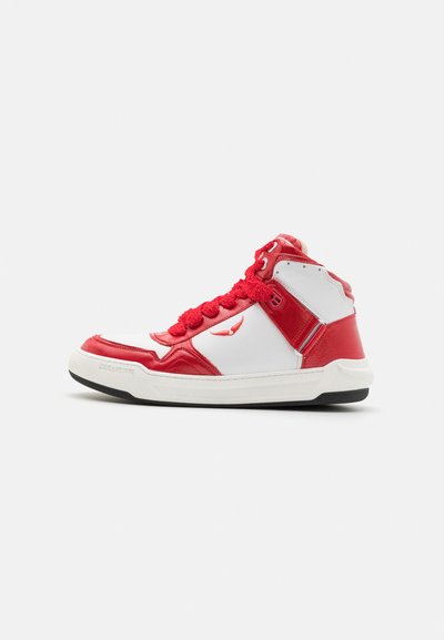 High-top sneakers featuring a white base with red leather accents, patterned red laces, and a textured sole. Notable logo on the side.