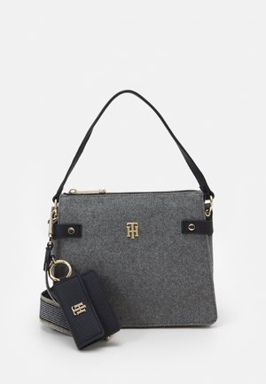 Bolso de fieltro gris con asa de cuero negro, correa de hombro a rayas desmontable y llavero de cuero negro, todos con detalles de logo en tono dorado.