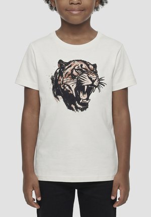 Enfant portant un t-shirt blanc avec un graphisme détaillé d'une tête de tigre rugissante sur le devant, assorti à un pantalon noir.