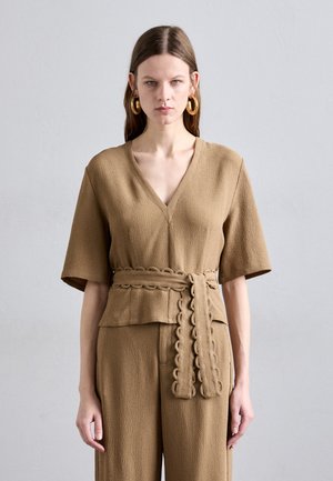 Top beige con texture, scollato a V e maniche corte, con una cintura abbinata a design scallop, abbinato a pantaloni a gamba larga.