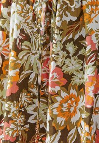 Floral-patterned fabric with shades of brown, orange, pink, and green. Lightweight material featuring a gathered design and drawstring detail.