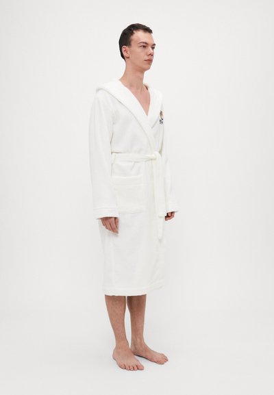 White terry bathrobe with a hood, shawl collar, and waist tie. Features two front pockets and an embroidered logo on the chest.