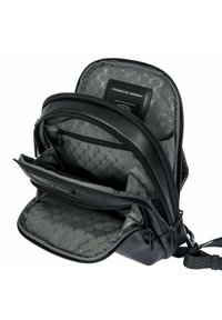 Borsa a tracolla in pelle nera con multiple tasche a zip aperte e foderatura interna con motivo esagonale grigio, dotata di etichetta Porsche Design.